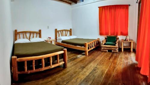 a bedroom with two beds and a red curtain at Green Lodge - Ayampe in Ayampe