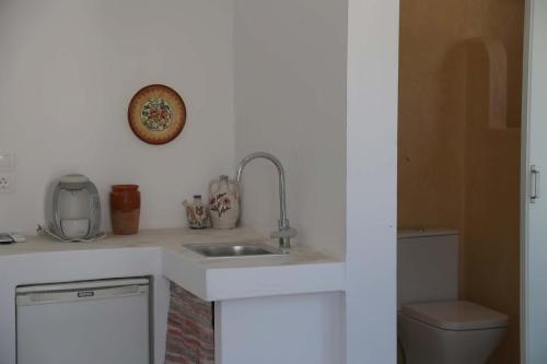 a white kitchen with a sink and a toilet at stamatia's rooms in Agios Kirykos