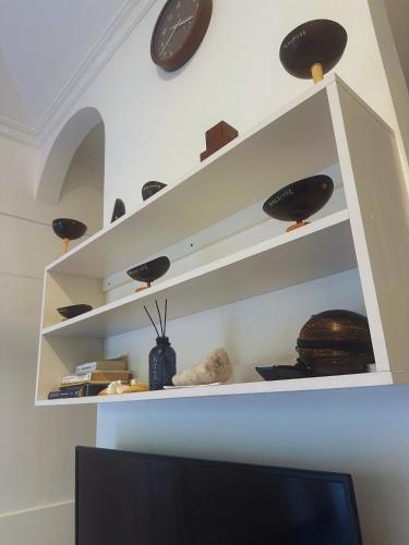 a shelf with bowls and a clock on a wall at Bahaaru Villa Surf and Stay in Himmafushi
