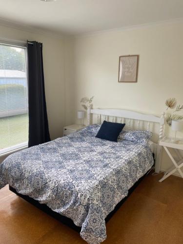 a bedroom with a bed with a blue comforter and a window at Phillip Island Central Cowes Pet Friendly Wifi Linen Towels Included Beach House in Cowes