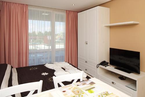 a room with a bed and a television and a table at Aparthotel Paradiso in Nesebar