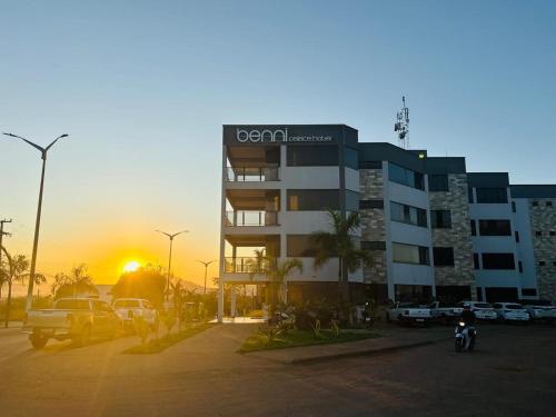 a building in a parking lot with the sunset in the background at Benni Palace Hotel in Parauapebas