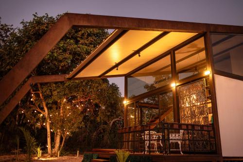 a house with a large window with a table and chairs at Chale Baru - AC - rio e ofuro - Cavalcante in Teresina de Goias