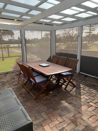 a patio with a wooden table and chairs on a patio at That Seaside Cottage - Fully equipped home, 4 Bedrooms on the foreshore in Tooradin
