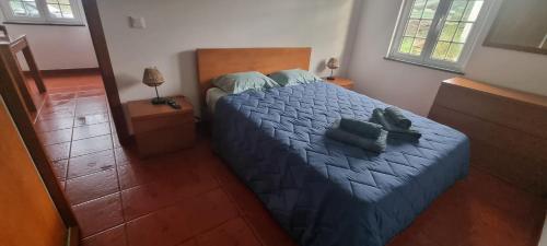 a bedroom with a bed with a blue comforter at Quinta do José - AL in Praia da Vitória