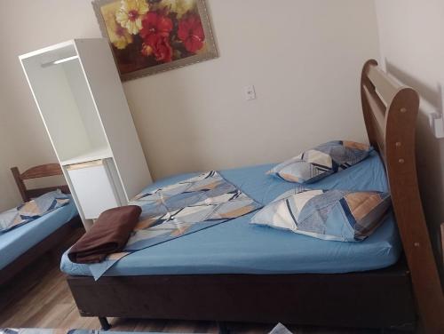 a small bedroom with a bed and a painting on the wall at Pousada San Valen in Aparecida