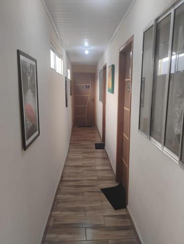 a corridor of a hallway with white walls and wooden floors at Pousada San Valen in Aparecida