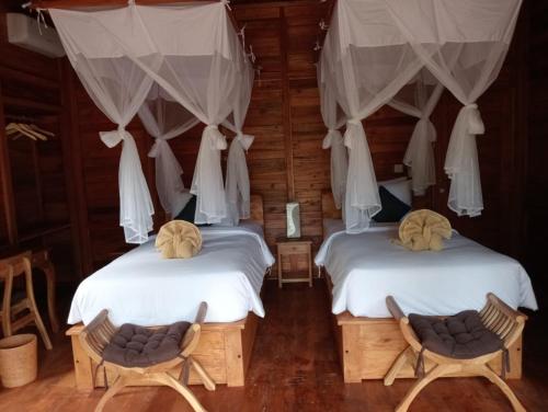 two beds in a room with two chairs at Loka Amertha in Sidemen