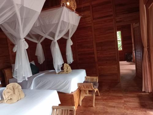 a bedroom with two beds with curtains and a chair at Loka Amertha in Sidemen