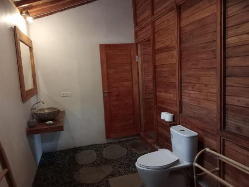 a bathroom with a toilet and a wooden door at Loka Amertha in Sidemen