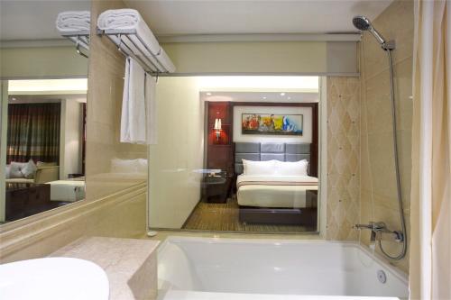 a bathroom with a tub and a bedroom with a bed at Bengal Blueberry in Dhaka
