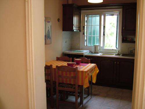 cocina con mesa, sillas y ventana en Spiridoula apartments en Agios Stefanos