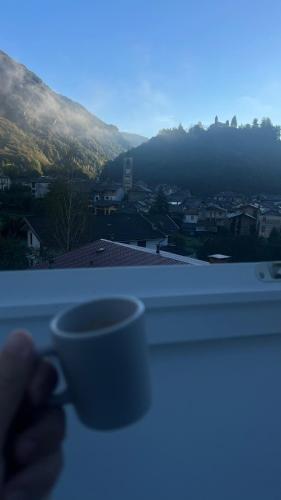 a person holding a coffee cup on a window sill at Spazio Oliveira Sparone in Sparone