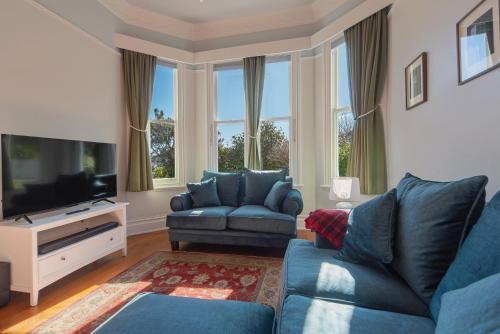 a living room with blue couches and a flat screen tv at Villa Cambria in Nelson