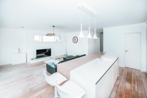 a white kitchen with white chairs and a kitchen island at Modern 2 Bed with Garden - Bridel in Bridel