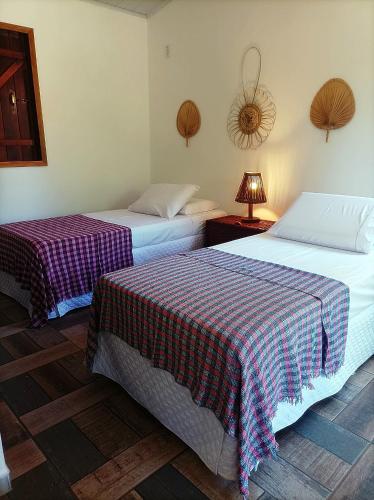 two beds in a hotel room with checked sheets at Pousada Luar do Sertão in Lençóis