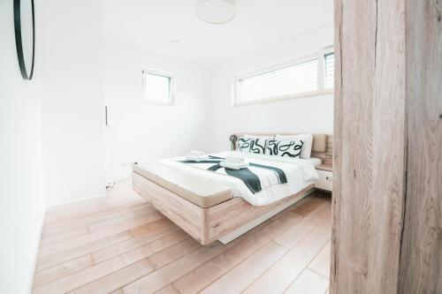 a white bedroom with a bed and a wooden floor at Modern 2 Bed with Garden - Bridel in Bridel