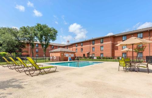 a group of chairs and a pool in front of a building at Extended Stay America Suites - Arlington - Six Flags in Arlington