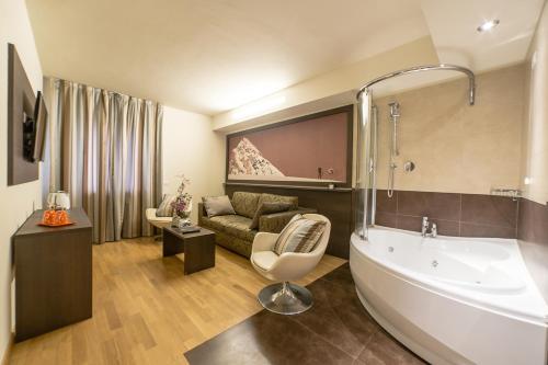 a bathroom with a bath tub and a living room at HB Aosta Hotel & Balcony SPA in Aosta