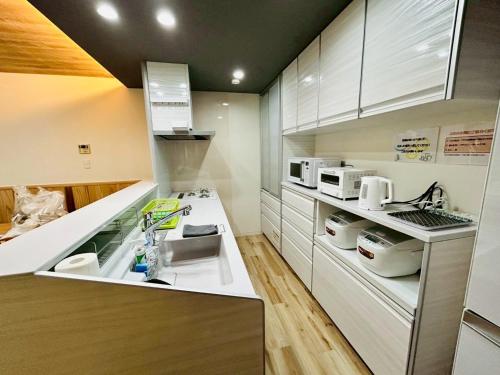a kitchen with white cabinets and a counter top at 時間を忘れる貸別荘オールブルーセカンド in Hatsukaichi