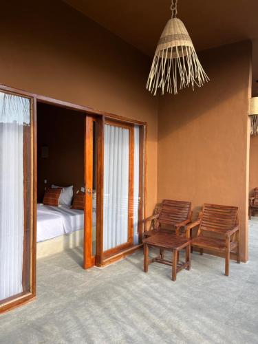 a bedroom with two chairs and a bed and windows at Fullmoon homestay in Kuta Lombok