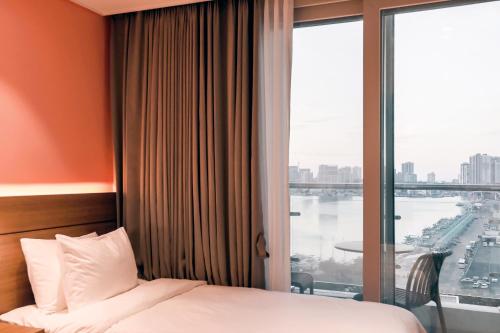 a hotel room with a bed and a large window at Hotelaround Sokcho in Sokcho