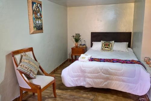 a bedroom with a large white bed and a chair at Rumi Wasi Inn Ollantaytambo in Ollantaytambo