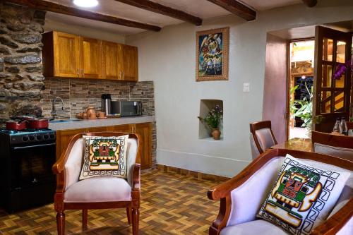 a kitchen with two chairs and a table and a stove at Rumi Wasi Inn Ollantaytambo in Ollantaytambo