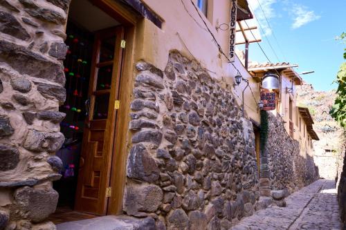 a stone building with a door on a street at Rumi Wasi Inn Ollantaytambo in Ollantaytambo