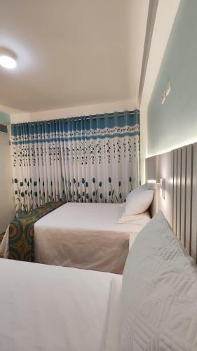a bedroom with two beds and a curtain at Mamre Guest House Tacna - Hospedaje in Tacna