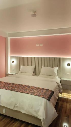 a bedroom with a large white bed with pink walls at Mamre Guest House Tacna - Hospedaje in Tacna