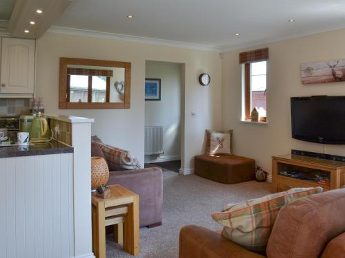 a living room with a couch and a tv at Pine Lodge in Sewerby