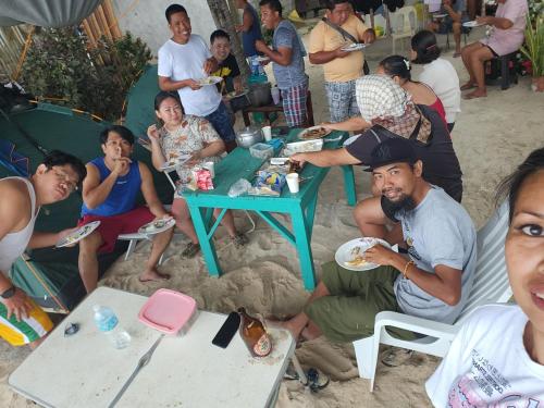 a group of people sitting around a table in the sand at Seashore Inn in Siquijor