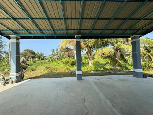 an empty pavilion with palm trees in the background at Homestay Kamilia in Bachok