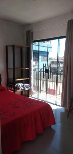 a bedroom with a red bed and a large window at Encanto Astral in São Thomé das Letras