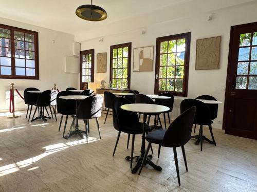 a room with tables and chairs and windows at Villa La Renaissance - Etretat in Étretat