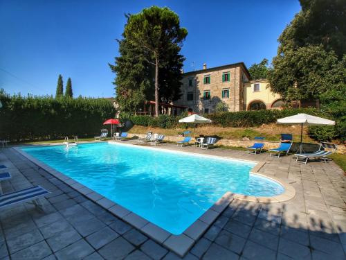 a swimming pool with chairs and umbrellas next to a building at Farmhouse with Pool – Pets Welcome! in Gualdo Cattaneo