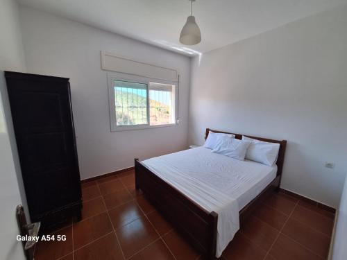a bedroom with a bed with white sheets and a window at Villa Diki beach in Tangier