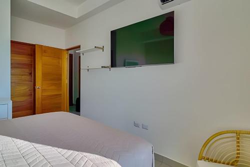 a bedroom with a bed and a tv on the wall at Caribbean Sunset Soak In Juan Dolio Beach Apt. in Juan Dolio