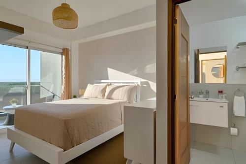 a white bedroom with a bed and a bathroom at Caribbean Sunset Soak In Juan Dolio Beach Apt. in Juan Dolio