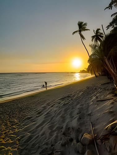 a person standing on the beach at sunset at Caribbean Sunset Soak In Juan Dolio Beach Apt. in Juan Dolio