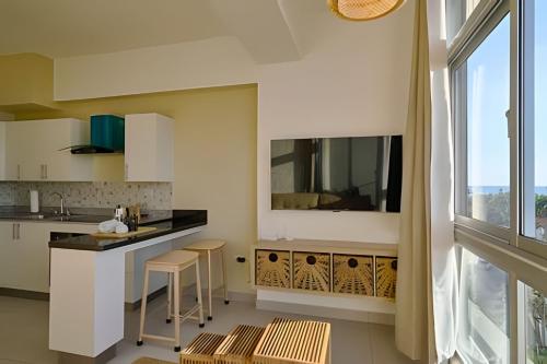 a kitchen with white cabinets and a large window at Caribbean Sunset Soak In Juan Dolio Beach Apt. in Juan Dolio