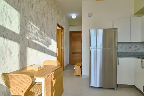 a kitchen with a refrigerator and a table and chairs at Caribbean Sunset Soak In Juan Dolio Beach Apt. in Juan Dolio