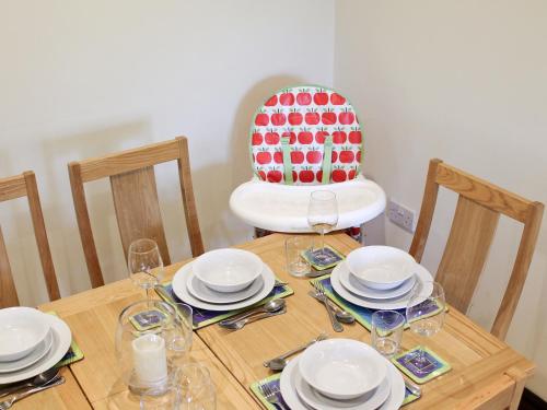 a wooden table with plates and glasses and a chair at Swallow Cottage in Shanklin