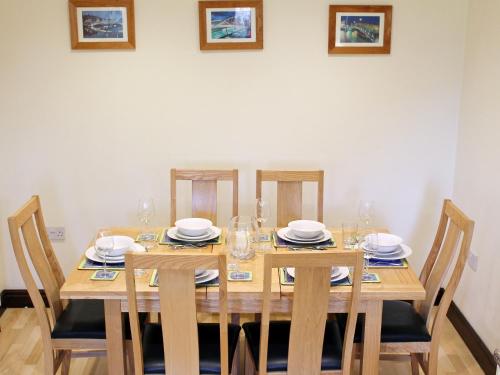 a wooden table with chairs and plates and glasses on it at Swallow Cottage in Shanklin