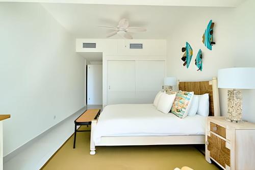 a white bedroom with a bed and a ceiling fan at Caribbean Sunscape Beachfront Apartment in La Puntica de Juan Dolio