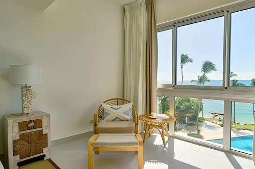 a living room with a chair and a view of the ocean at Caribbean Sunscape Beachfront Apartment in La Puntica de Juan Dolio