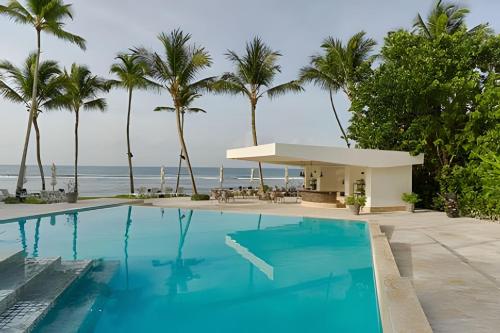 La Puntica de Juan DolioにあるCaribbean Sunsets Views Apartmentのヤシの木が茂る海のそばのスイミングプール