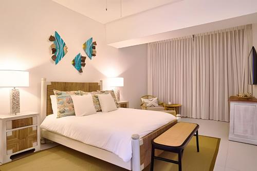 a bedroom with a large bed and a chair at Caribbean Sunscape Beachfront Apartment in La Puntica de Juan Dolio