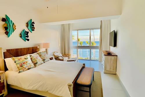 a bedroom with a bed and a view of the ocean at Caribbean Sunscape Beachfront Apartment in La Puntica de Juan Dolio